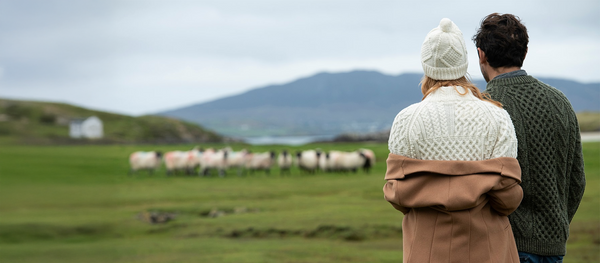 Sweatershop.com Aran Sweaters and hats, A Couple checking on a few sheep