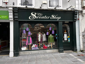 Storefront of 'The Sweater Shop Kilkenny' with mannequins wearing sweaters in a city street setting.